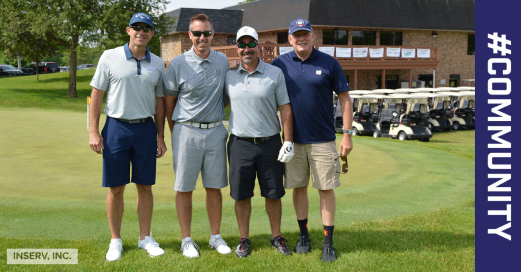 Four male INSERV employees stand together in a line. They are standing on a golf course.